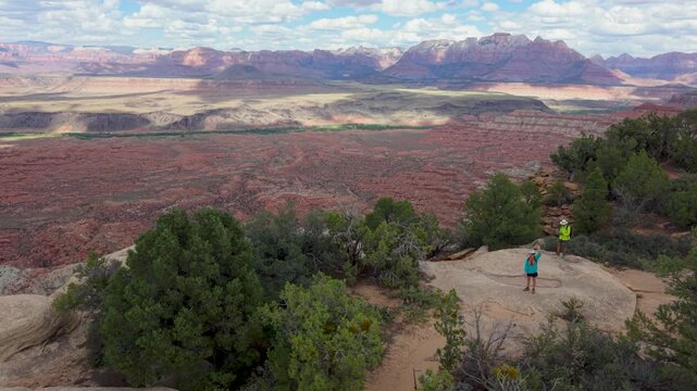 Aerial view of senior couple hiking on Gooseberry Mesa while enjoying views of Zion National Park in Utah. Rocky landscapes surround them.