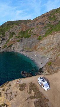 La Frana Beach in Sardinia, Italy showcases breathtaking landscapes with crystal-clear waters and rocky cliffs. a couple on vacation in a camper van