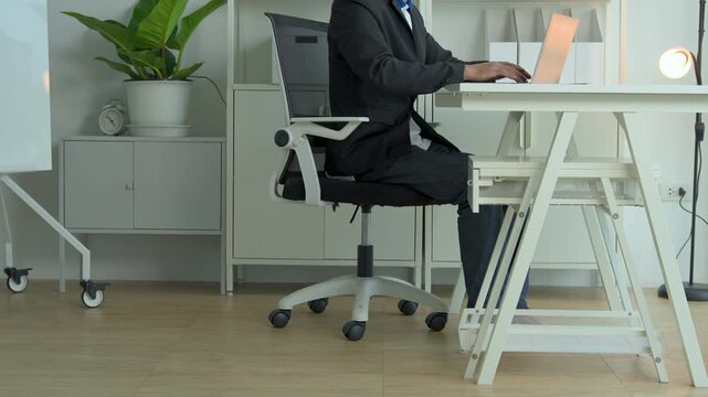 Professional man working on a laptop at a clean white desk in a modern bright office workspace