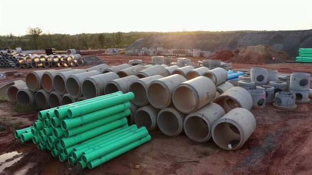 Large concrete culvert pipe, green PVC sewer pipe and precast catch basins wait in the utility yard of a data center build in Louisa County, Virginia, as the sun drops. Aerial view