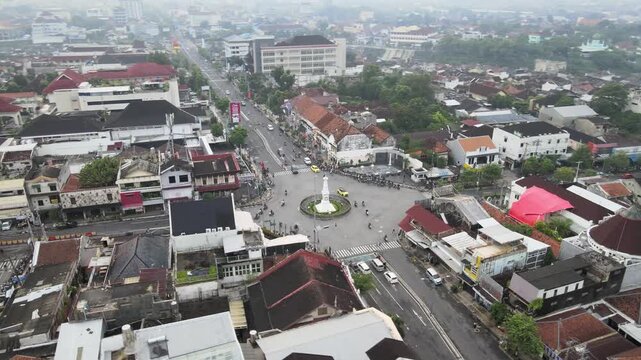 Aerial circling shot of Tugu Yogyakarta landmark and city traffic, Indonesia