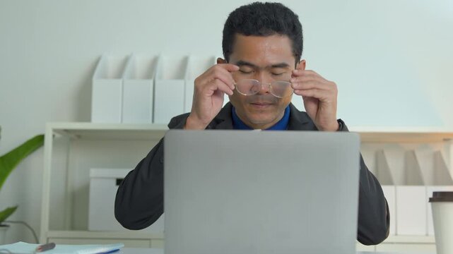 Professional man in a suit working on a laptop computer at a clean modern office desk space