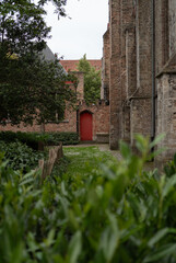 Obraz premium Red door in Bruges courtyard garden