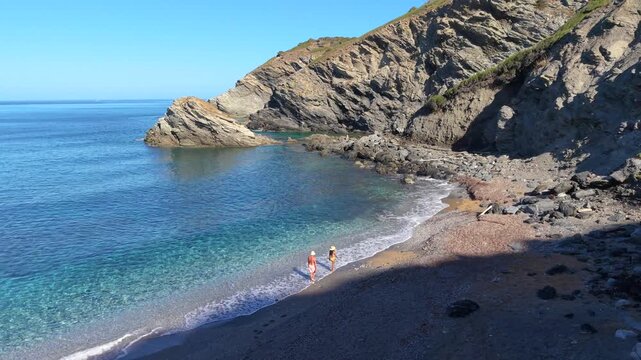 Crystal clear waters embrace the rocky coastline of La Frana Beach in Sardinia, Italy. Visitors enjoy the stunning landscape and tranquil atmosphere, making it an ideal vacation spot for relaxation.