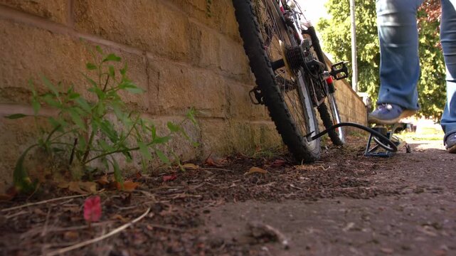 Cyclist pumping flat tyre on bicycle