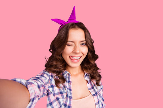 Self-portrait of nice cheerful cheery girlish attractive adorable funky flirty mood wavy-haired lady wearing checkered shirt showing tongue out isolated over violet pastel background