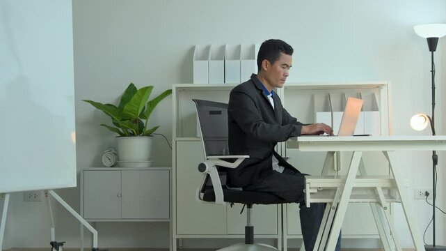 Professional man working on a laptop at a clean white desk in a modern home office environment