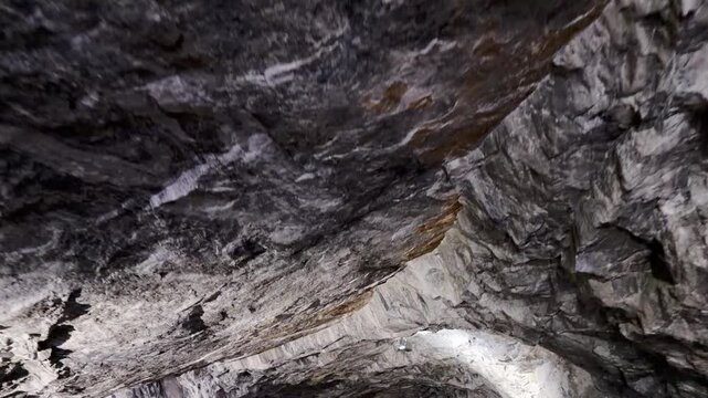 A small lamp illuminates a rough stone ceiling inside a cave at Ruskeala, Karelia. Bright light cuts through the darkness. The mysterious view creates a sense of wonder.