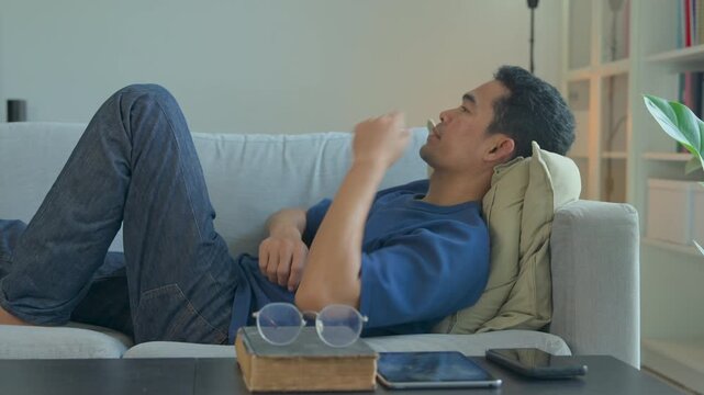 A contemplative man resting on a comfortable sofa in a bright and modern living room interior
