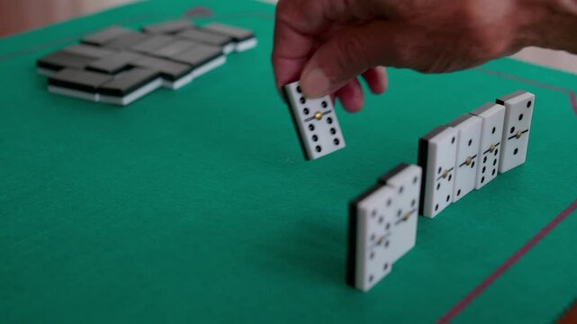 People playing dominoes game on green tablecloth