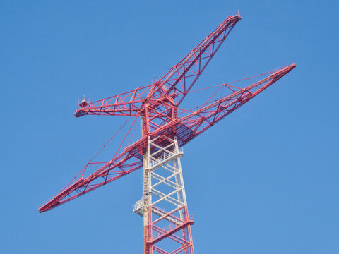 Low angle view of the top section of the famous red and white steel electricity pylon of Torre Faro against a vibrant blue sky, Messina, Sicily, Italy.