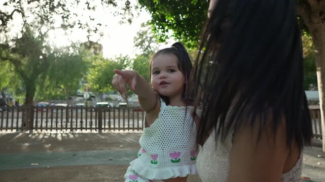 Young mother playing with daughter on playground slide