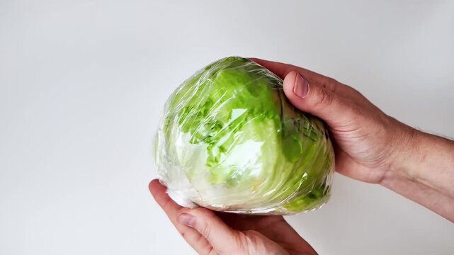 Two hands hold a head of iceberg lettuce wrapped in clear plastic film against a white background, shown in three sequential vertical frames