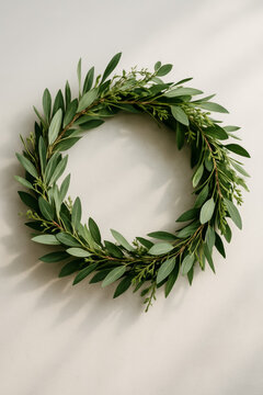 Circular green leaf wreath casting soft shadows on white
