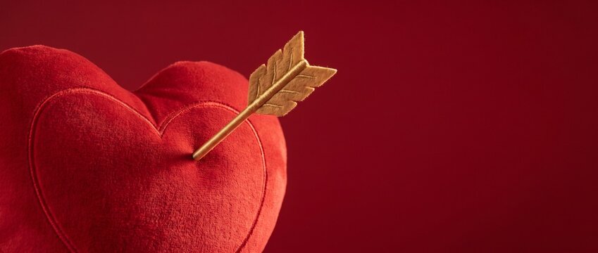 Soft red heart with an arrow on a deep red background  