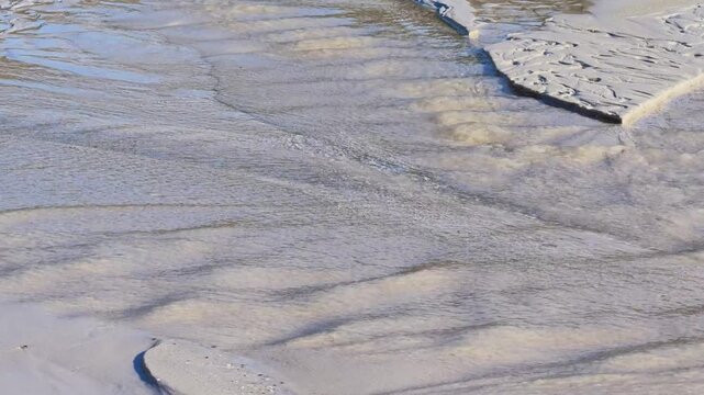 Small water channels create natural patterns and textures in the pale sand at low tide on Haukland Beach, Vestvagoya, Lofoten Islands, Norway.
