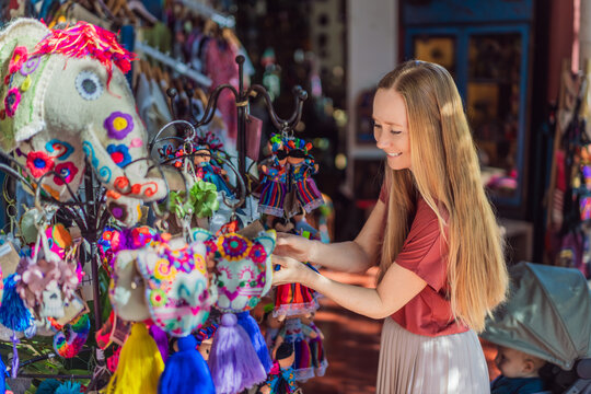 Female tourist looks at traditional dolls and souvenirs in a folk art shop, showing Mexican culture, craft market and travel shopping concept