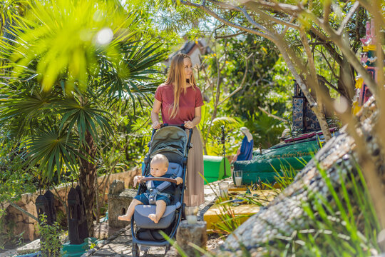 Woman pushing baby stroller through traditional Mexican cemetery during Day of the Dead, exploring colorful cultural heritage with her infant in Mexico