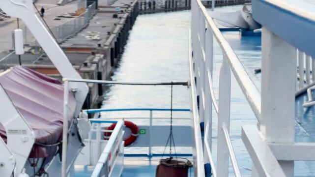 Water churns with white foam as a cruise ship moves along the Neva River. The powerful movement creates an exciting and energetic feeling. Looking over the deck railing brings a joyful sense adventure