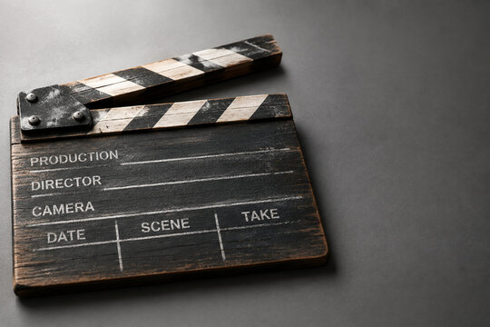 Weathered wooden film clapperboard on grey surface for filmmaking and cinema production concept