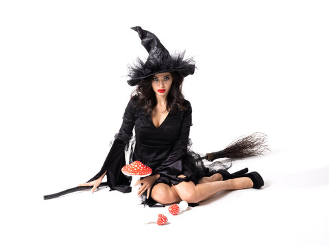 A beautiful witch in a black dress flies on a broomstick