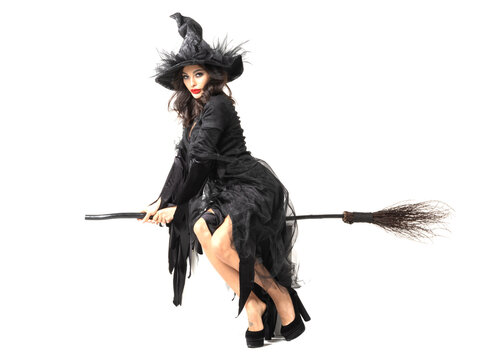 A beautiful witch in a black dress flies on a broomstick