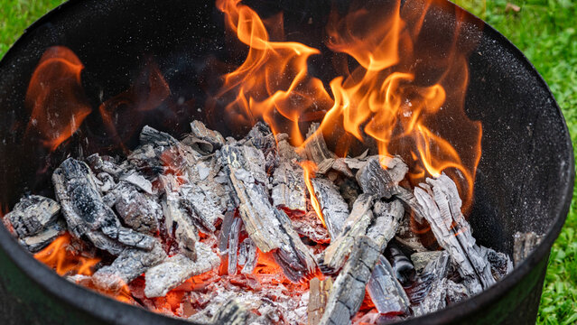 view of a bright and hot, colorful fire in an iron barrel, making a fire, burning