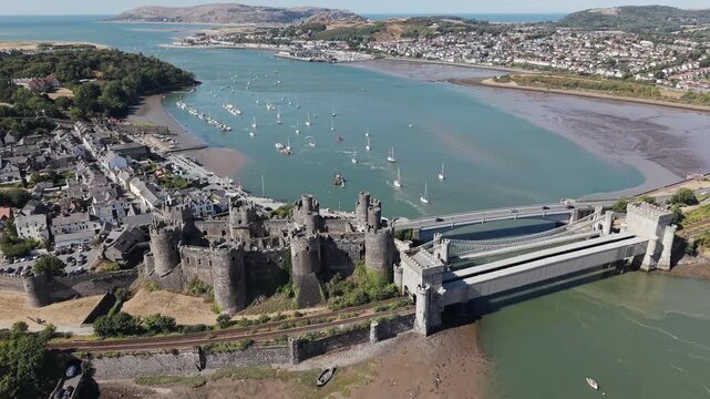 Aerial view of Conwy Castle and surrounding estuary in North Wales, medieval fortress standing beside stone bridges and river bank