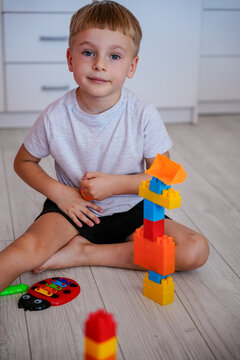 Little boy playing with constructor blocks on the floor and looking at camera.