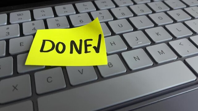 Done checkmark sticky note on laptop keyboard close up