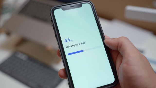 Hand holding smartphone with app deleting user data and showing data deleted confirmation