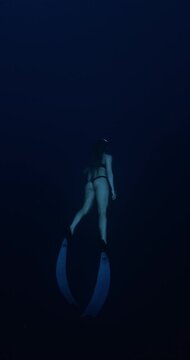 Freediver woman with long fins underwater in deep ocean