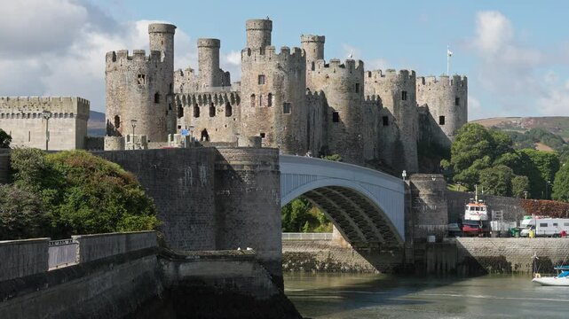 Conwy Castle towering above the iron suspension bridge and River Conwy estuary in North Wales, sunny day view across water