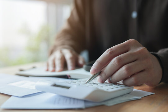 close up man hand press on calculator and check invoice letter from bank to check about debt and spending monthly for people lifestyle and inflation economic concept