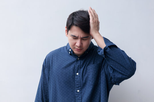 close up young asian man frowned with stressful and use hand massage on head to relief headache for unhealthy lifestyle concept