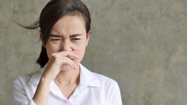 southeast asian female young adult grimacing and covering nose from foul stench in real life, genuine disgusted reaction