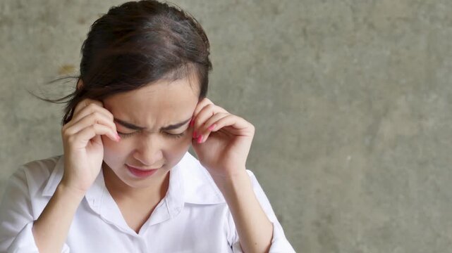 southeast asian young woman with bilateral headache and throbbing temples, painful facial expression