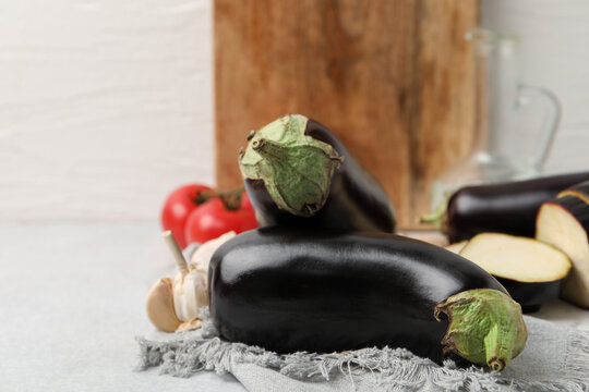 Fresh raw eggplants and other products on light grey table, closeup. Space for text