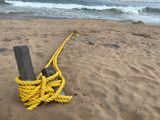Yellow rope tied to wooden posts on the beach and Scenic Vizag Rushikonda Beach Coastline Landscape Shot During Cloudy and Rainy Weather in the Evening at Rushikonda, Visakhapatnam © AI Digital Art