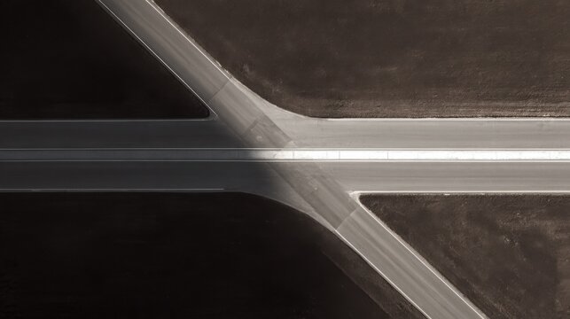 Luxury conceptual aerial photography of a perfectly clean road splitting into two distinct directions at the center of the frame, one branch bright