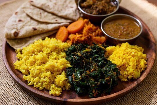 The Indian Thali Plate with vibrant yellow rice, saag, roti, and chutneys