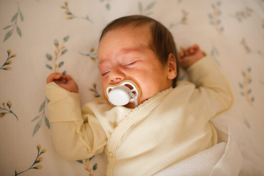 Cute infant baby sleeping in crib with pacifier close up top view. Childhood.
