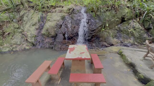Kathu Dam waterfall water gently flowing down the rocks surrounded by lush green trees flowers and tables Patong on the Island of Phuket Thailand