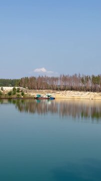 Serene Quarry Lake with Industrial Barge and Pine Forest Reflection
