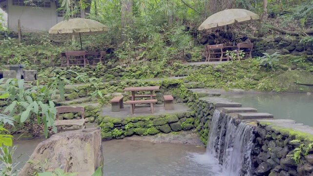 Kathu Dam waterfall water gently flowing down the rocks surrounded by lush green trees flowers and tables Patong on the Island of Phuket Thailand