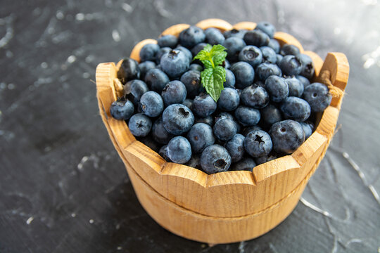 fresh ripe blueberries on a dark textured background. Healthy organic summer berries with green mint leaves.