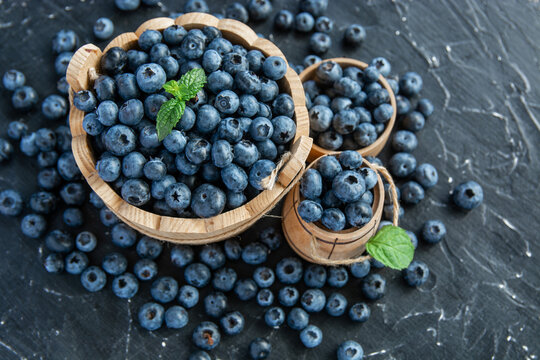 fresh ripe blueberries on a dark textured background. Healthy organic summer berries with green mint leaves.
