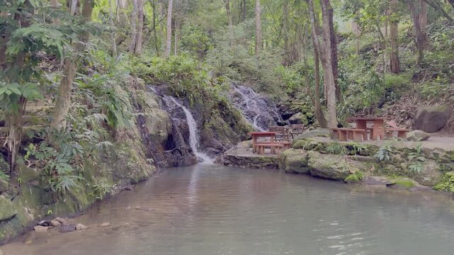 Kathu Dam waterfall water gently flowing down the rocks surrounded by lush green trees flowers and tables Patong on the Island of Phuket Thailand