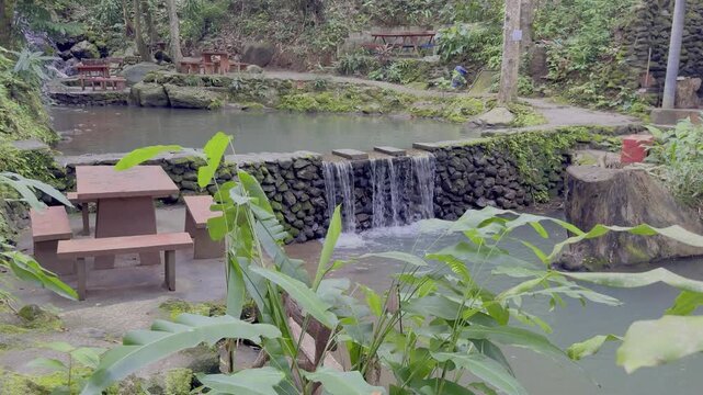 Kathu Dam waterfall water gently flowing down the rocks surrounded by lush green trees flowers and tables Patong on the Island of Phuket Thailand