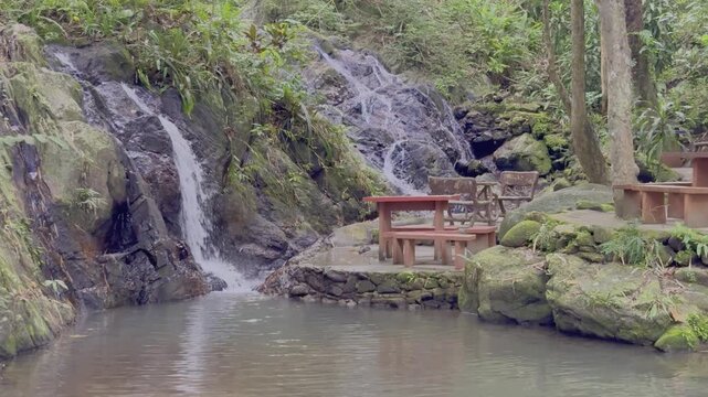 Kathu Dam waterfall water gently flowing down the rocks surrounded by lush green trees flowers and tables Patong on the Island of Phuket Thailand